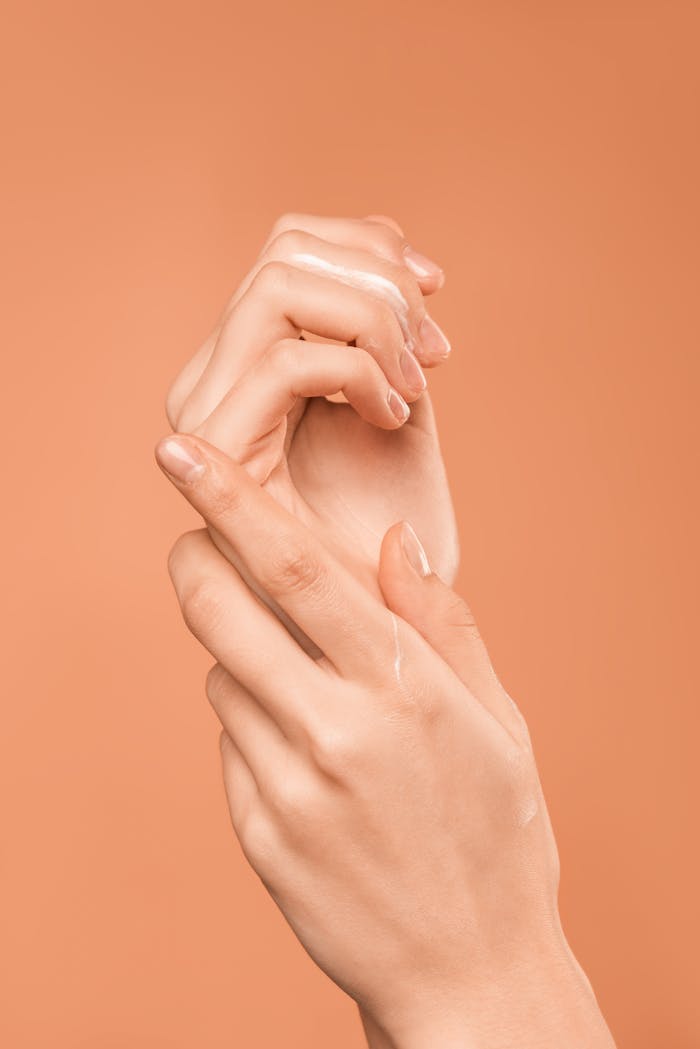 Mastering the First Impression: Your intriguing post title goes here Close-up of hands with oil on peach background, emphasizing skincare and wellness.