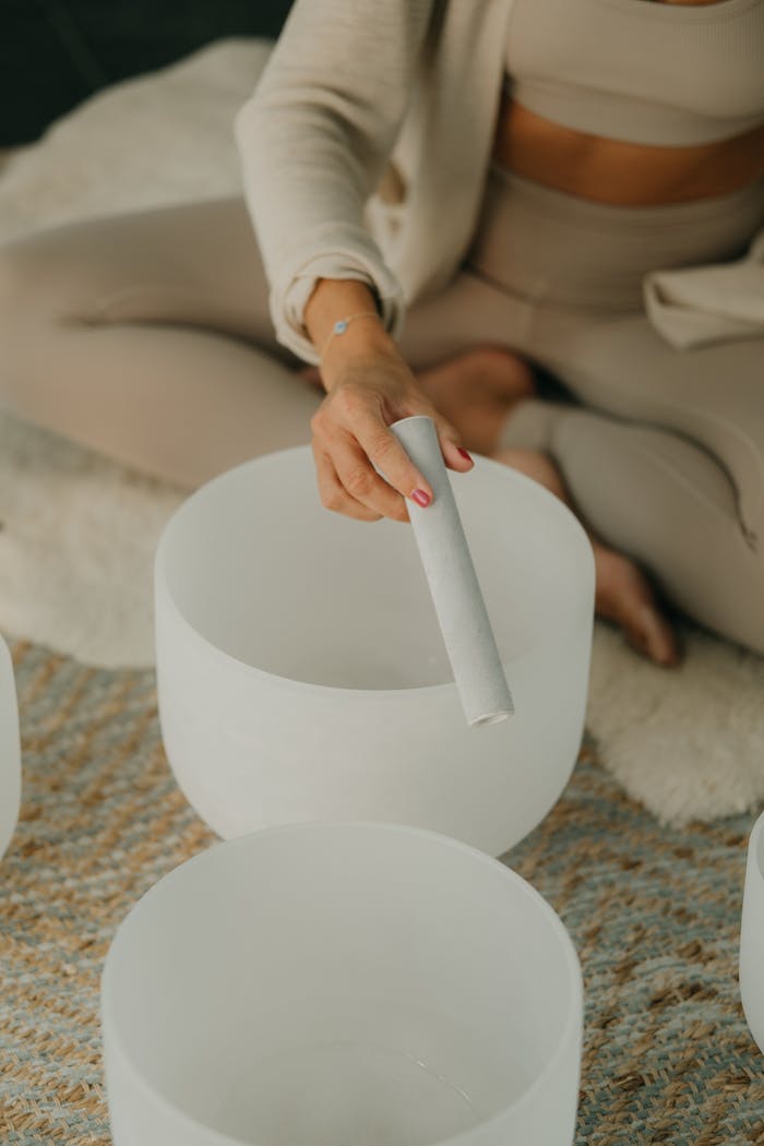 The Art of Drawing Readers In: Your attractive post title goes here A woman in neutral tones playing a crystal singing bowl for meditation and relaxation.